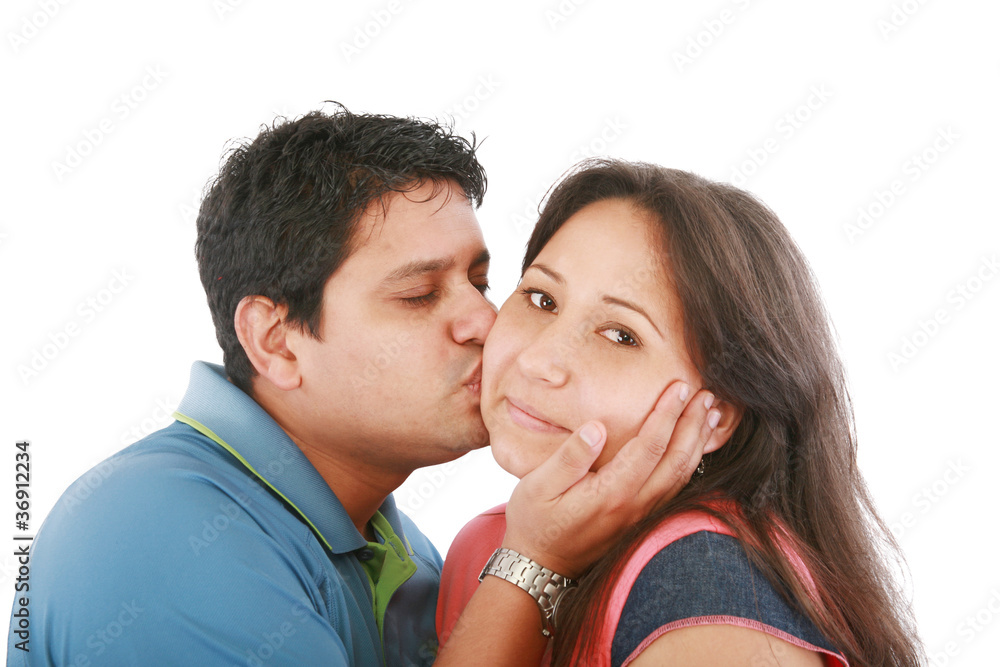 Portrait of woman looking at camera with man near by kissing her Portrait of woman looking at camera with man near by kissing her
