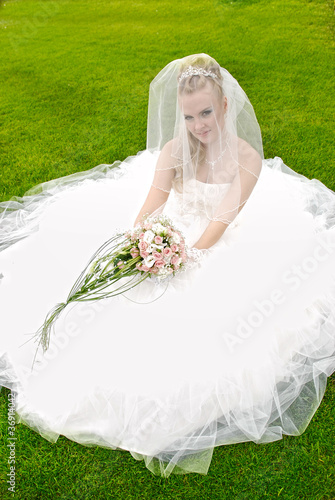 Beautiful bride posing in her wedding day at the grass photo