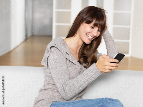 young woman smiles as she looks at her mobile phone
