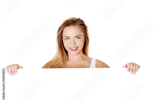 Beautiful blond teen girl behind big blank billboard photo