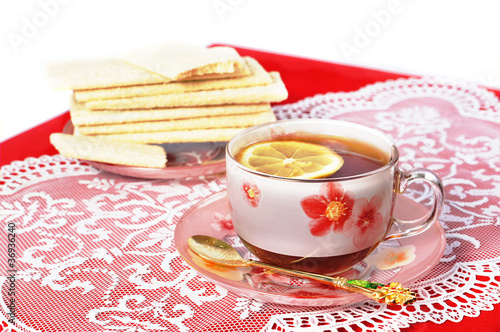 Cup of black tea with a lemon on a red cloth