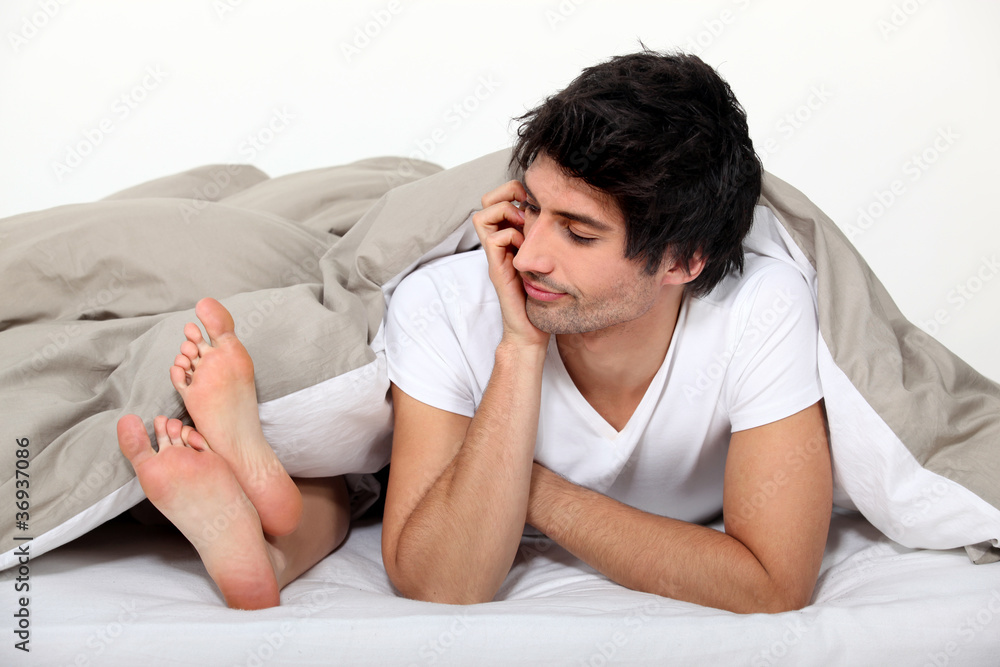 Man looking at his partner's feet in bed Man looking at his partner's feet in bed