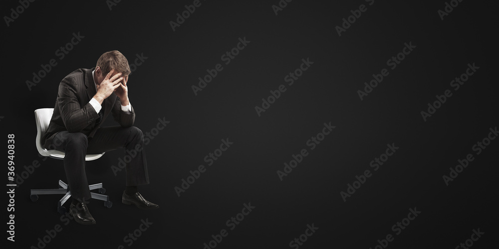 Young businessman sitting on chair with head down as Young businessman sitting on chair with head down as