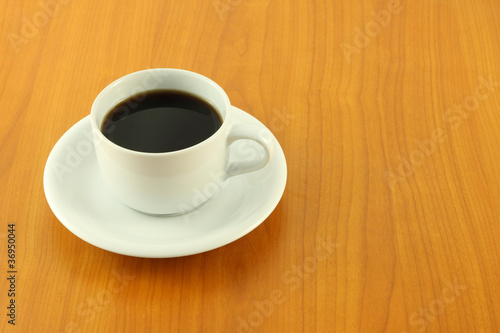 White cup of black coffee on wooden table.