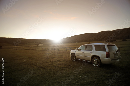 off-road vehicles in a field at sunset