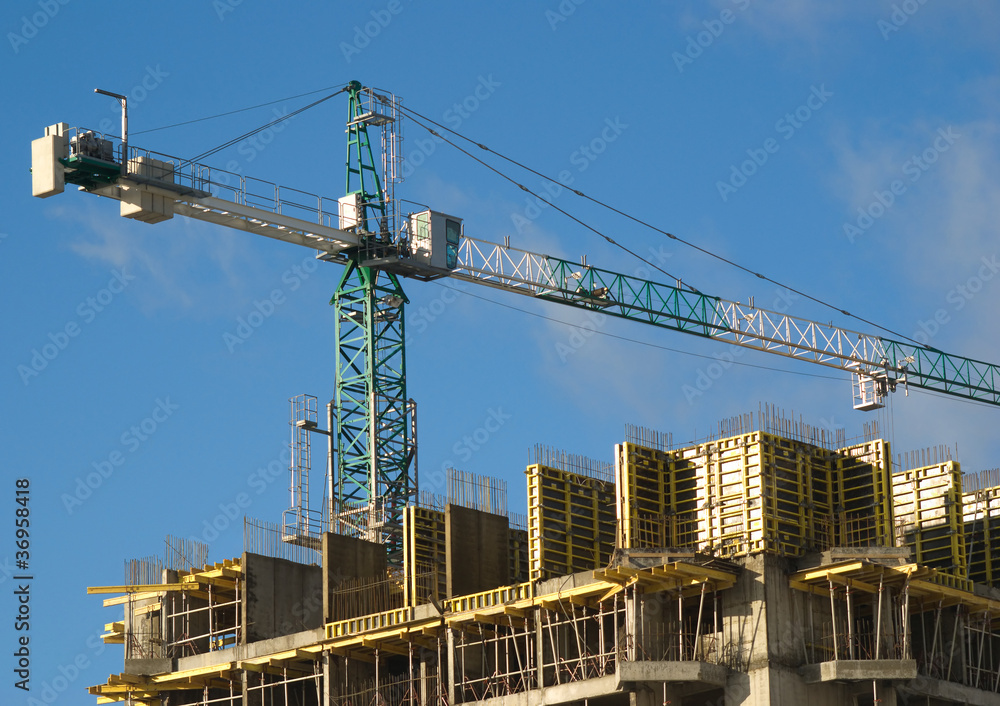 Hoisting tower crane above building house