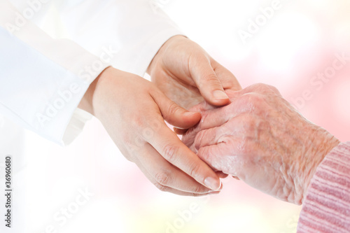 Doctor holding senior lady's hand