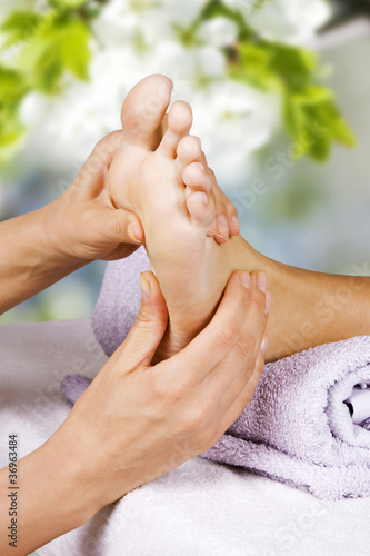 Obraz na płótnie Foot (feet) massage in the spa salon. Young woman having feet massage in spa salon. Feet care. Well-groomed female foot. Woman receiving foot massage, close up w salonie