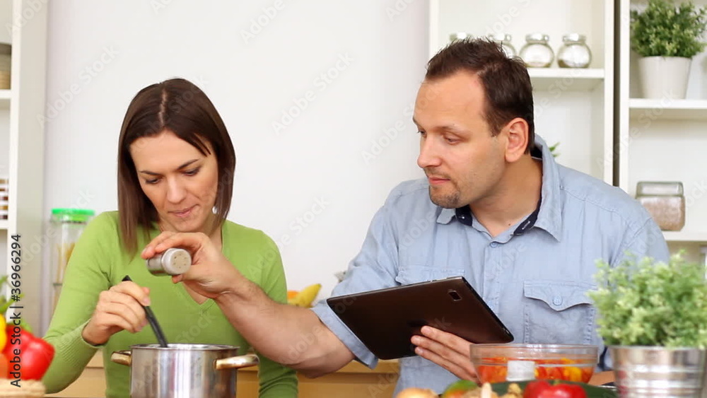 Couple using a tablet computer during cooking Couple using a tablet computer during cooking