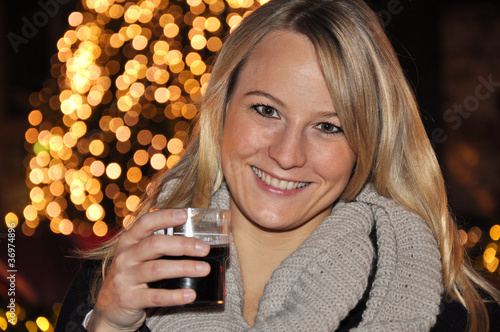 Junge Frau trinkt Glühwein auf Weihnachtsmarkt photo