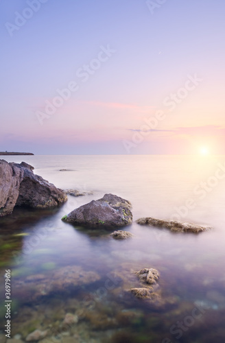 Rock in sea on sunset.
