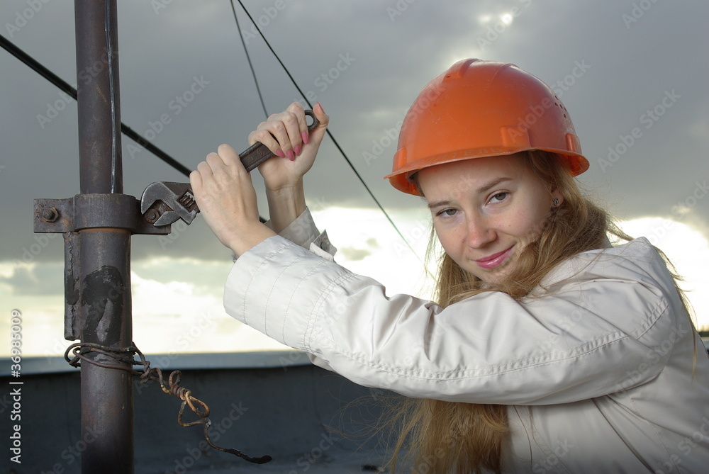 Smiling girl with a wrench in an orange helmet Smiling girl with a wrench in an orange helmet
