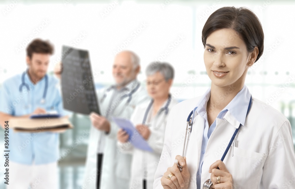 Mid-adult female doctor medical team in background Mid-adult female doctor medical team in background
