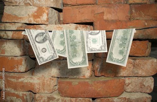 Dollars hang on a rope against a bricks photo