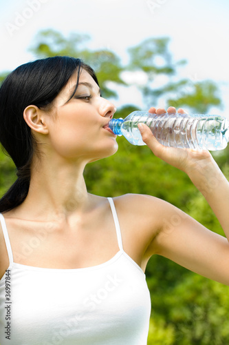 Woman drinking water at workout, outdoors