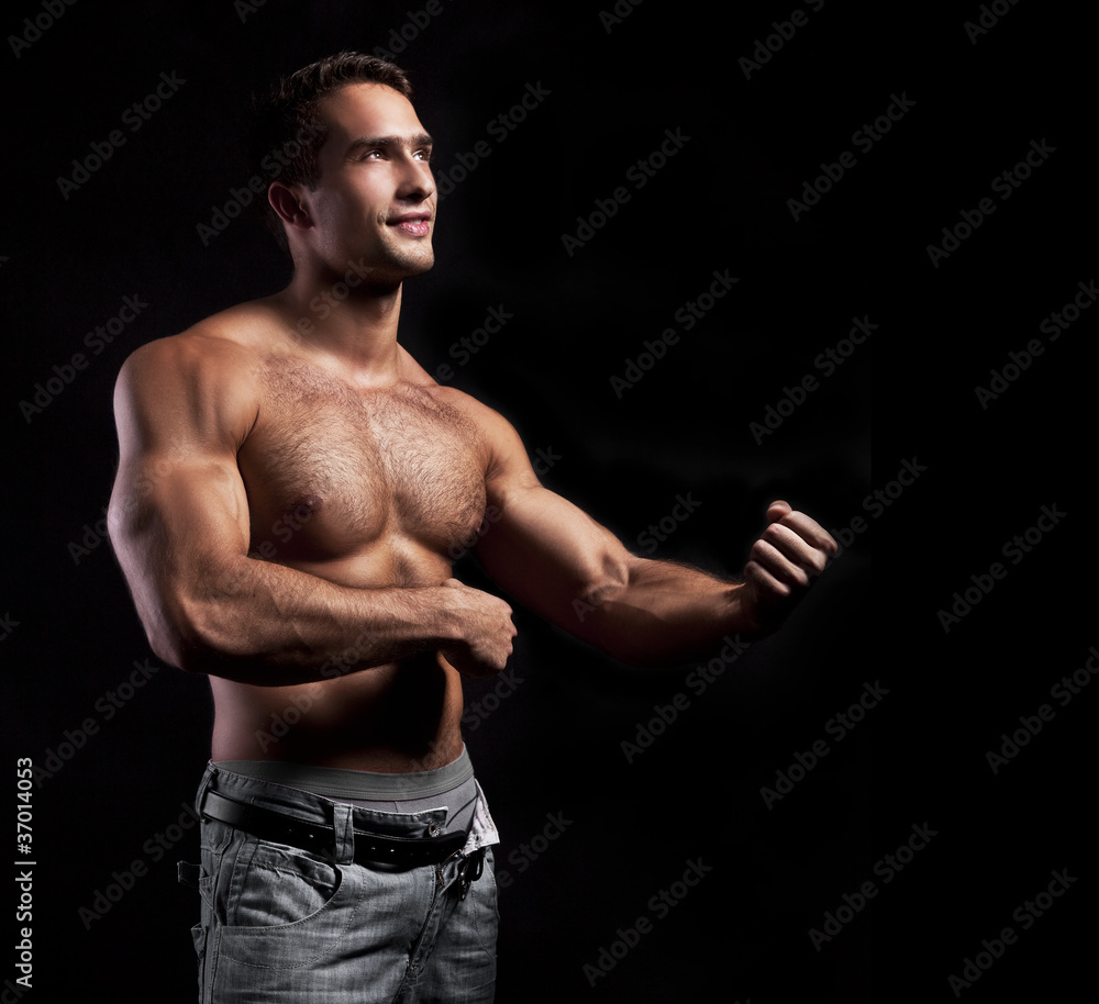 Naklejka premium young muscular smiling man on black background
