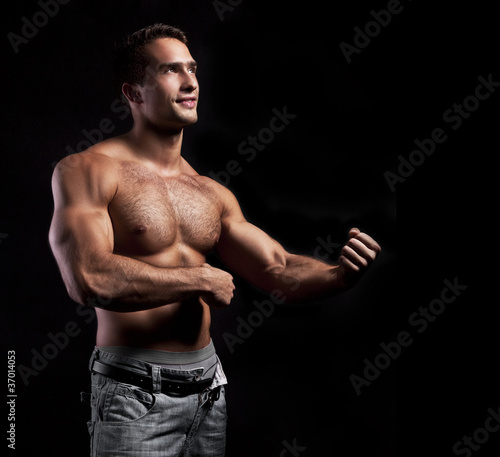 young muscular smiling man on black background