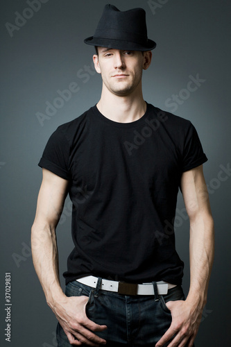 Young handsome man posing in black t-shirt and black hat.
