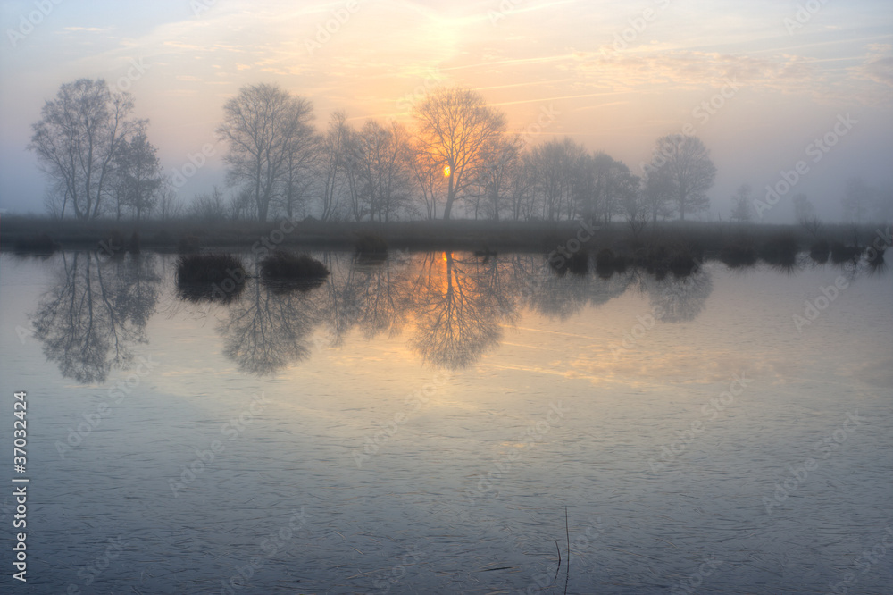 Fototapeta premium Rising sun above a frozen lake
