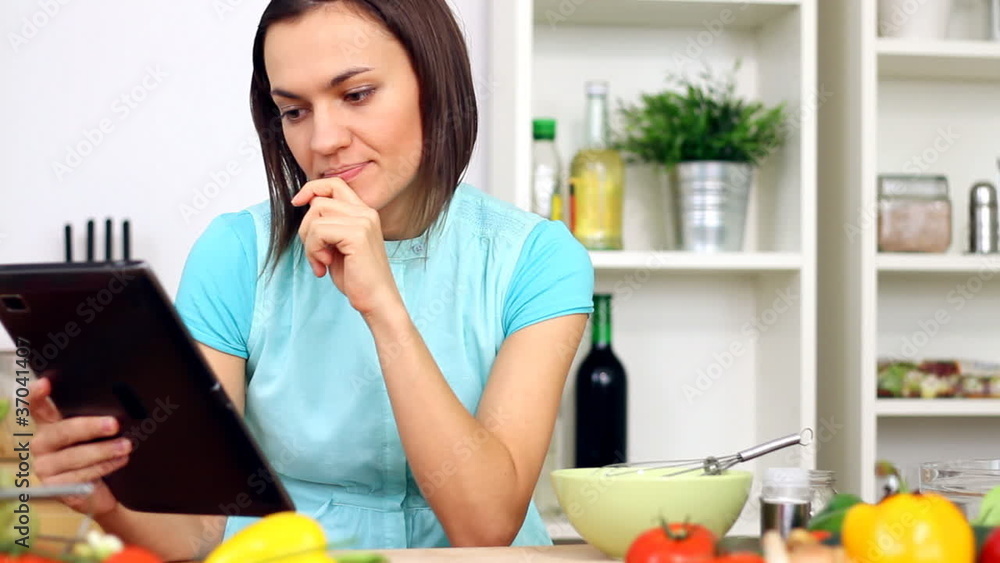 Woman cooking with help of digital tablet Woman cooking with help of digital tablet