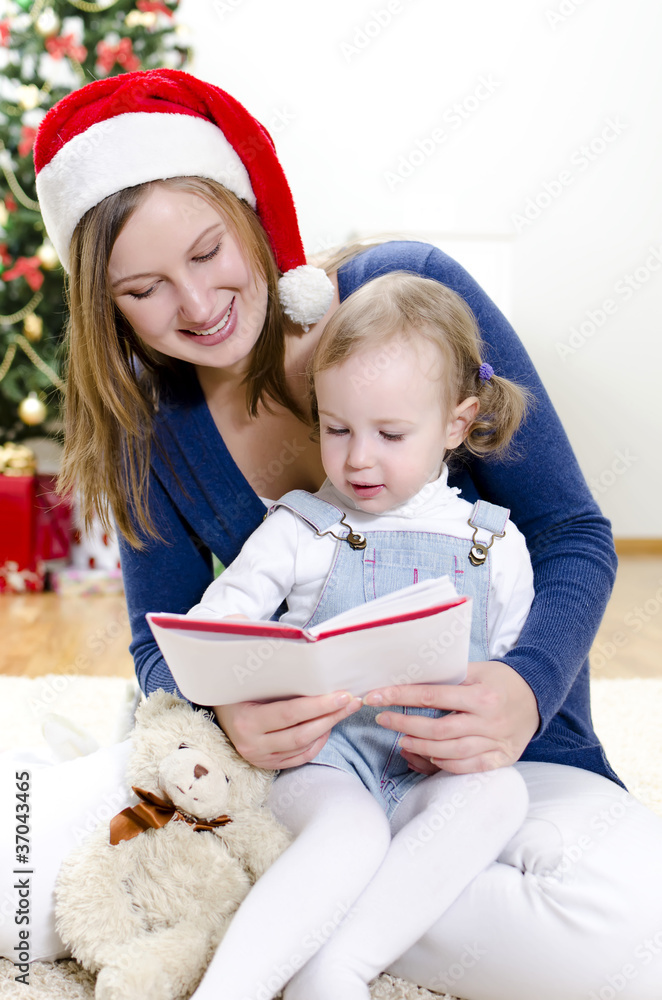 Girl and her mom reading book at Christmas Girl and her mom reading book at Christmas