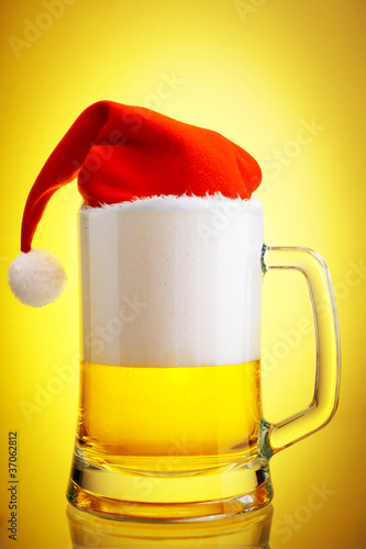 Beer and hat of Santa Claus on a yellow background