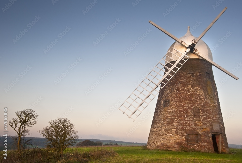 Traditional old wooden and brick windmill at sunset