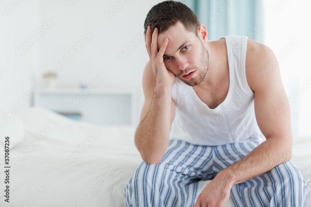 Depressed man sitting on his bed Depressed man sitting on his bed