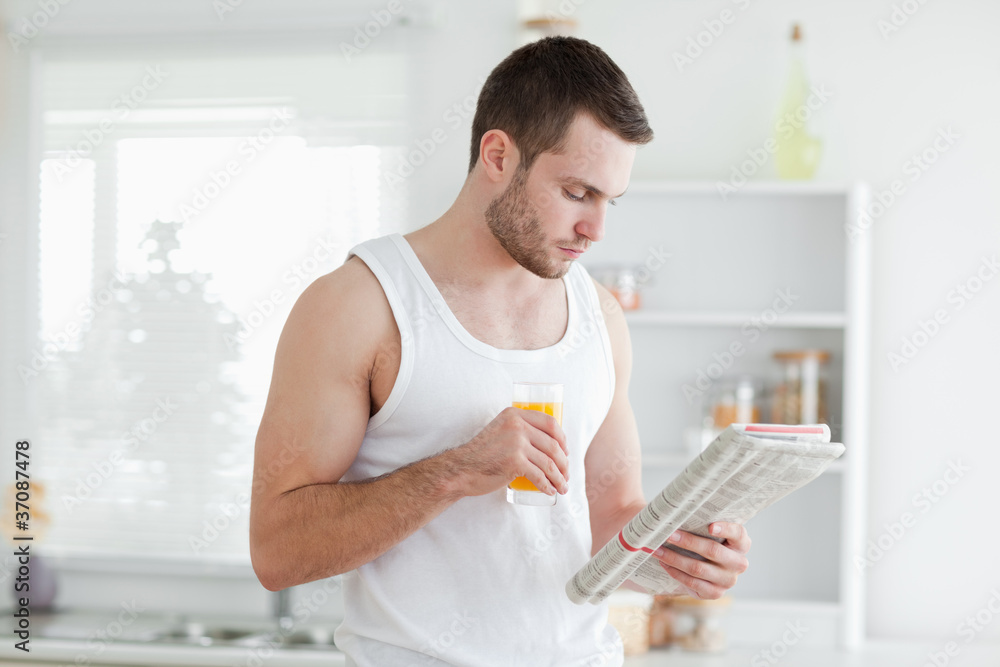 Man drinking orange juice while reading the news Man drinking orange juice while reading the news