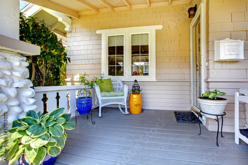 Covered entrance porch with plants and chair. photo