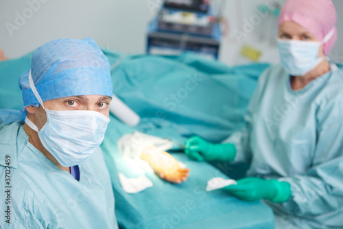 Surgeon and nurse performing hand operation