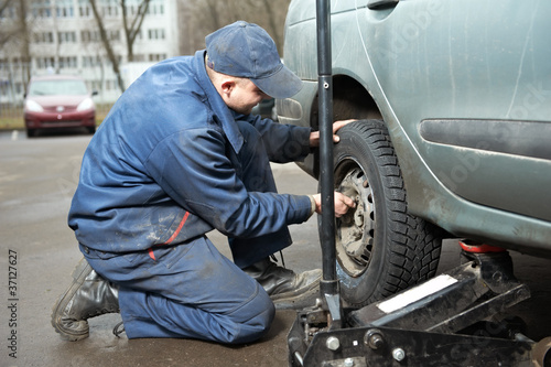 machanic repairman at tyre fitting with car jack