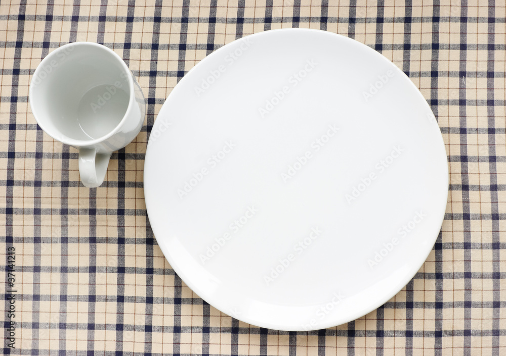 Plate and cup on tablecloth. Plate and cup on tablecloth.