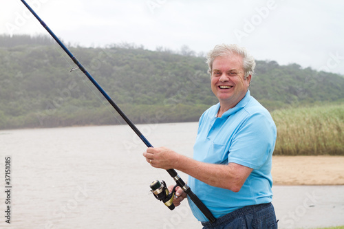 happy senior man fishing by the pond