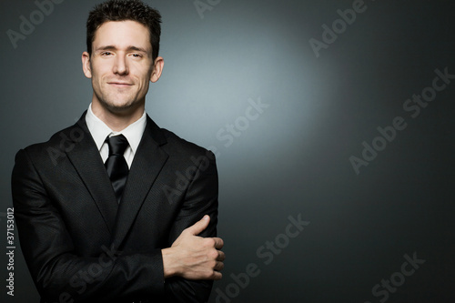 Handsome businessman in black suit expressing positivity.