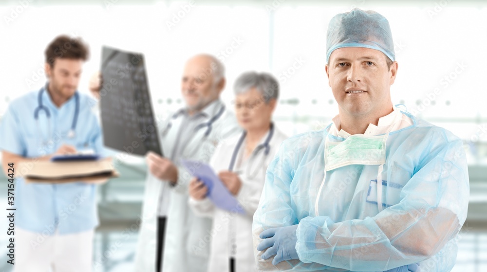 Mid-adult surgeon with medical team in background Mid-adult surgeon with medical team in background