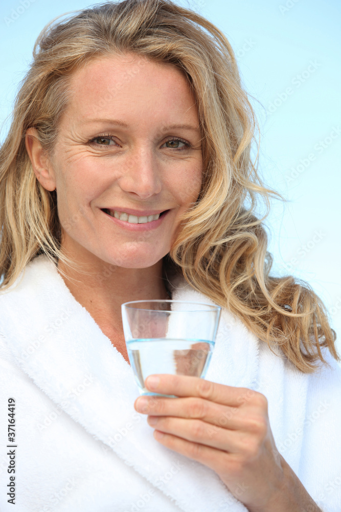 Woman drinking a glass of water in a bathrobe Woman drinking a glass of water in a bathrobe
