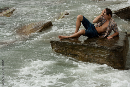 brawny lad on stone at sea
