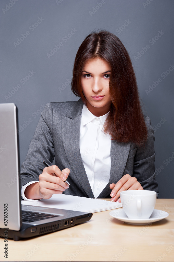 A pretty concentrated woman working with her laptop and papers. A pretty concentrated woman working with her laptop and papers.