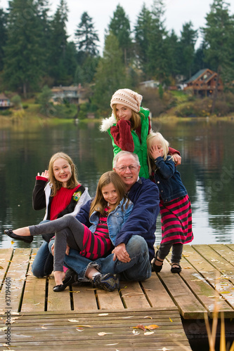 A happy gray haired Grandpa with 4 Grandchildren on a lake