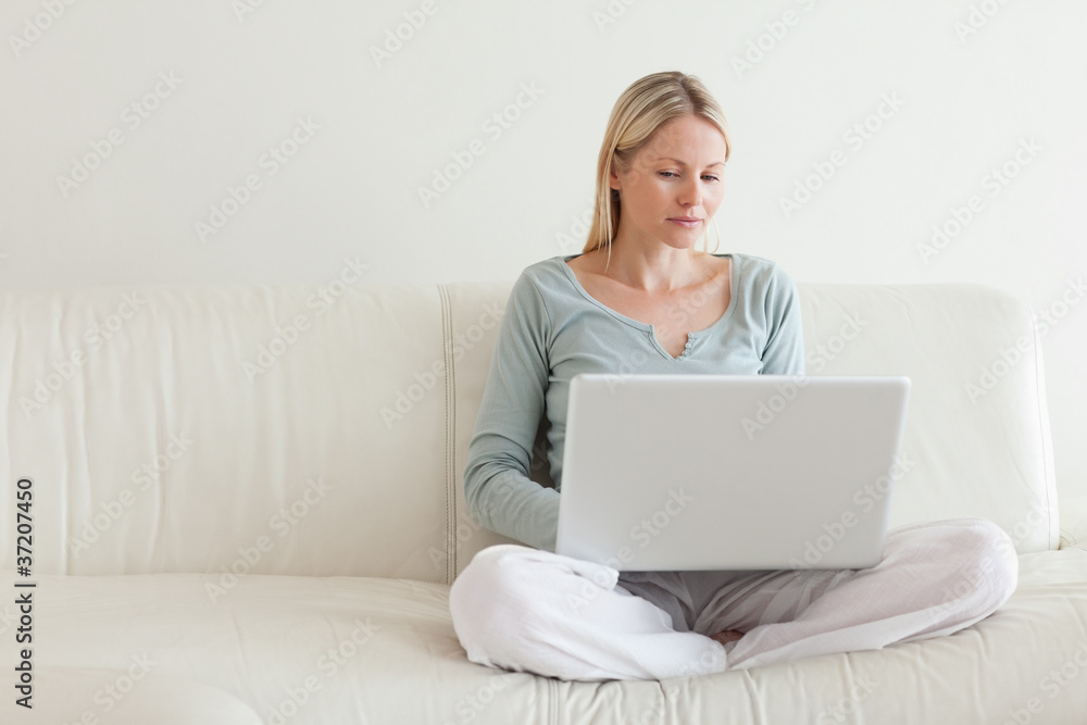Woman sitting cross legged on the couch with her notebook Woman sitting cross legged on the couch with her notebook