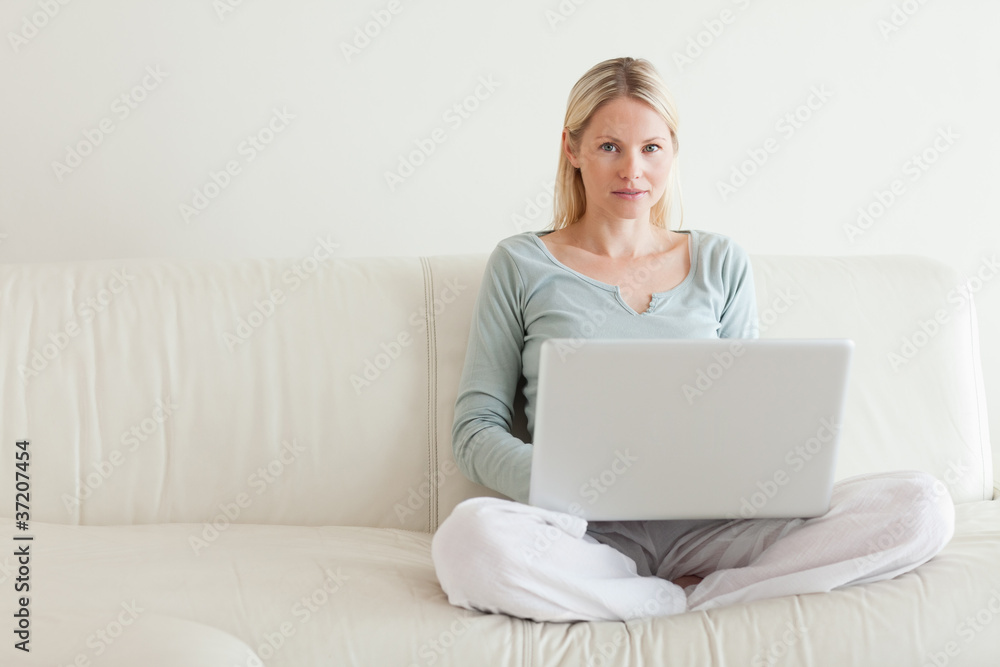 Woman sitting cross legged on the sofa with her notebook Woman sitting cross legged on the sofa with her notebook