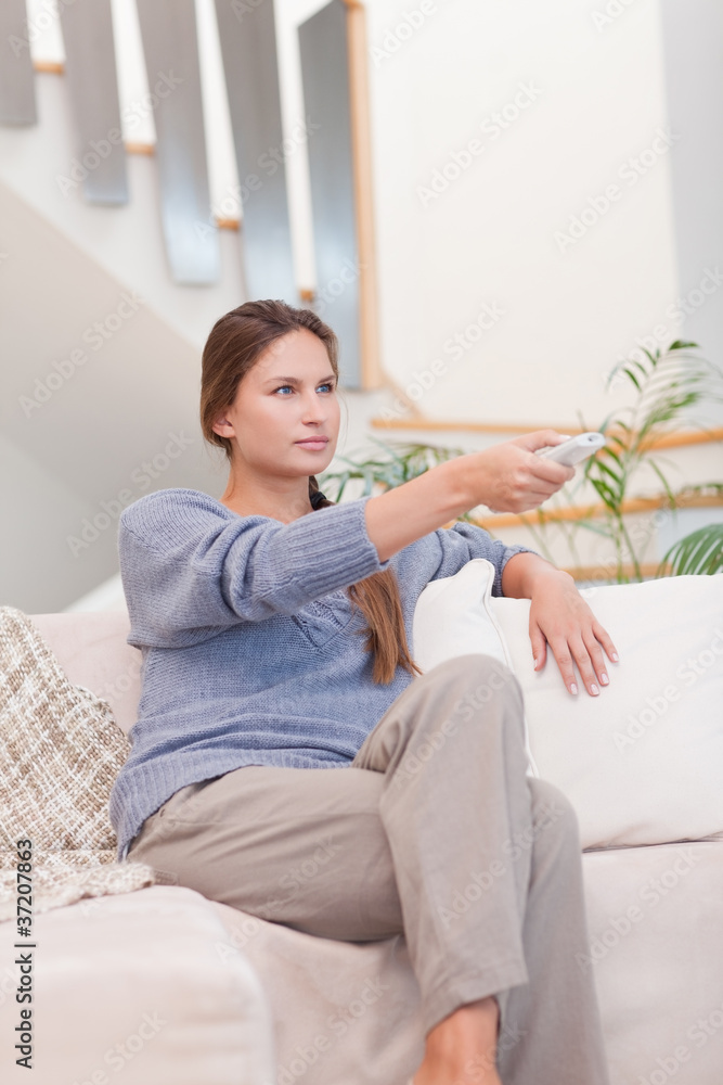 Portrait of a woman switching channel with a remote Portrait of a woman switching channel with a remote