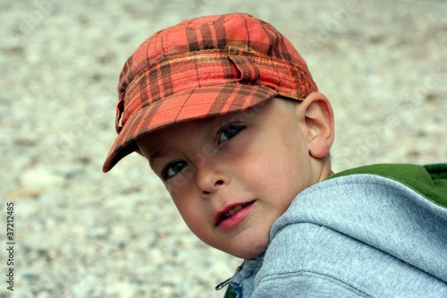 Small child in a cap looking up with interest