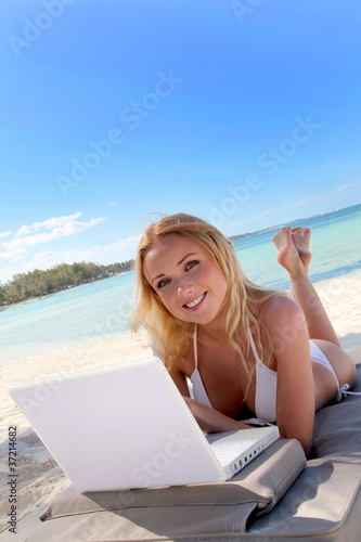 Beautiful blond woman at the beach with laptop computer