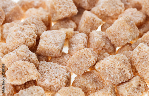 Many brown lump cane sugar cubes , food background