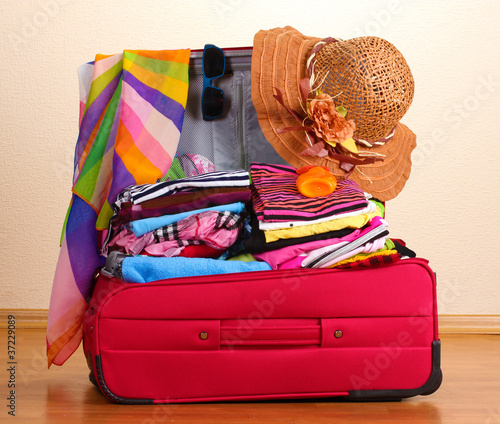 Open red suitcase with clothing in the room photo