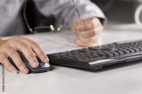 male model hand clicking a mouse and holding glasses.