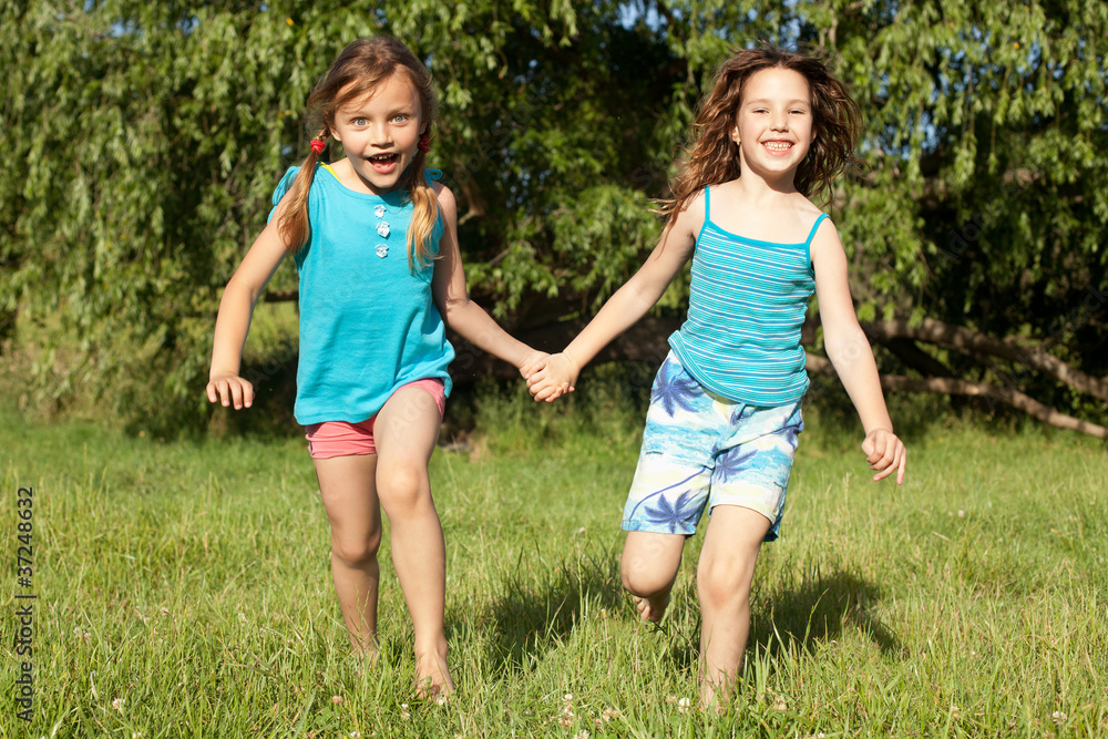 children running through a field holding hands