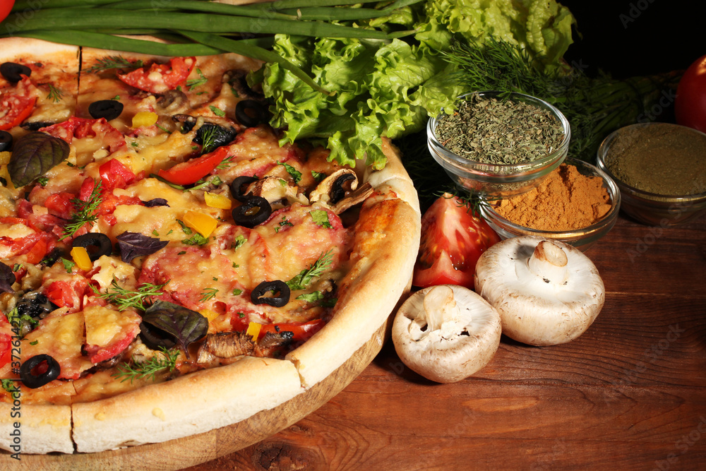 delicious pizza, vegetables and spices on wooden table